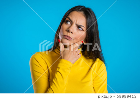 Thinking woman looking around on blue background. Worried contemplative face expressions. Beautiful young hispanic model. 59999415