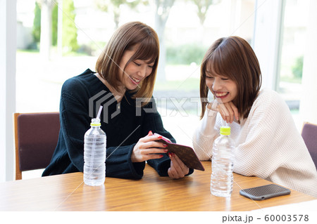 スマートフォン見ながら談笑する女性 60003578