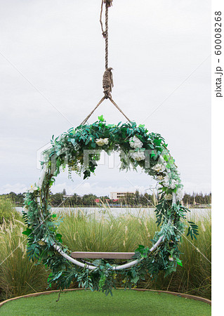 Hanging vintage wooden swing decorated with flowers and leaf. The design for decor place at outdoor Hanging vintage wooden swing decorated with flowers and leaf. The design for decor place at outdoor 60008268