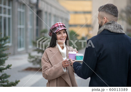 Happy young woman taking a cup of coffee 60013389