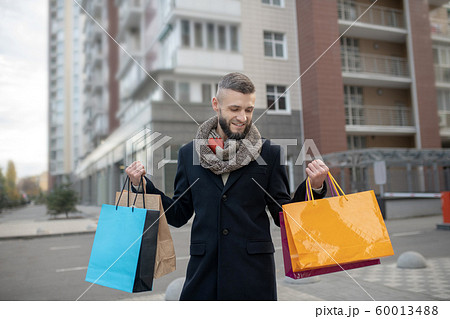 Handsome young man holding many shopping bags 60013488
