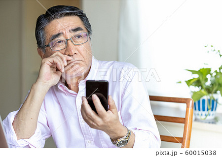 スマホを見るシニア男性　への字口 60015038