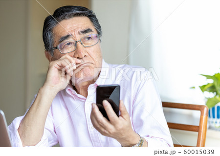 スマホを見るシニア男性　への字口 60015039