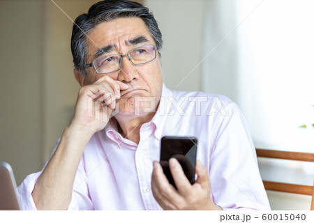 スマホを見るシニア男性　への字口 60015040