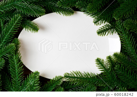 Top view of white plate surrounded with fir tree Top view of white plate surrounded with fir tree 60018242
