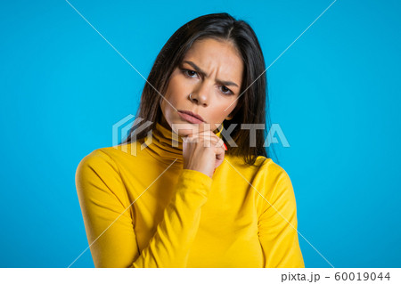 Thinking woman looking around on blue background. Worried contemplative face expressions. Beautiful young hispanic model. Thinking woman looking around on blue background. Worried contemplative face expressions. Beautiful young hispanic model. 60019044