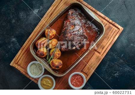 Baked meat and potatoes. A delicious and hearty meal. A large baked piece of meat. Cooked hot food. 60022731