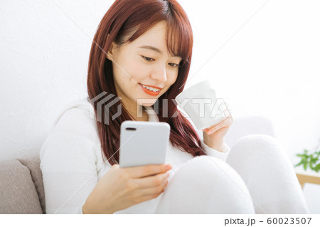 コーヒーを飲みながらスマホを見る女性 コーヒーを飲みながらスマホを見る女性 60023507