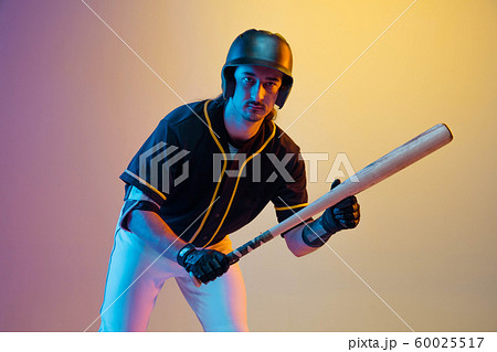 Baseball player, pitcher in a black uniform practicing on gradient background in neon light 60025517