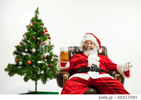 Santa Claus drinking beer near Christmas tree, congratulating of New Year 2020 60027085