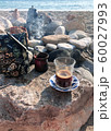 Transparent glass with coffee on a saucer. Turkish coffee and a steaming teapot in the background. Making coffee on a sandy beach among the stones. Perfect morning. 60027993