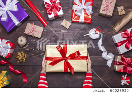 Woman holding Christmas present in gold gift box 60028939