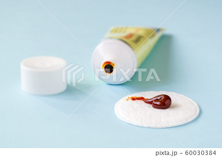 An iodine ointment on a cotton pad near an open tube. Salve for wound disinfection. 60030384