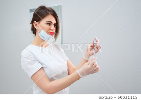 cosmetologist holds syringe filled with gel medication cosmetologist holds syringe filled with gel medication 60031115