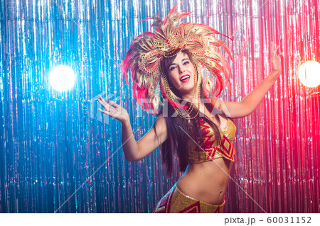 Cabaret, dancer and holidays concept - Cute young girl in bright colorful carnival costume on dark background 60031152