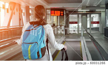 Woman on escalator with backpack and suitcase in airport terminal. Woman on escalator with backpack and suitcase in airport terminal. 60031266