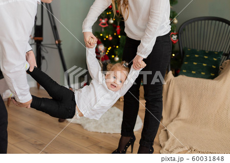 Happy dad and mom swing their daughter in their 60031848