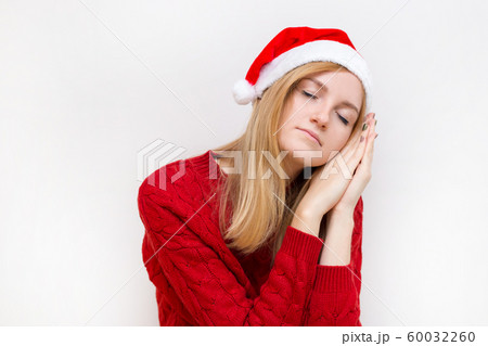 Beautiful woman wearing christmas hat over isolated background smiling doing sleep gesture with hand. Holiday concept. Emotion facial expression. 60032260