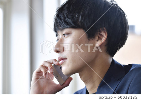 スマートフォンで通話する若い男性　横顔　アップ 60033135