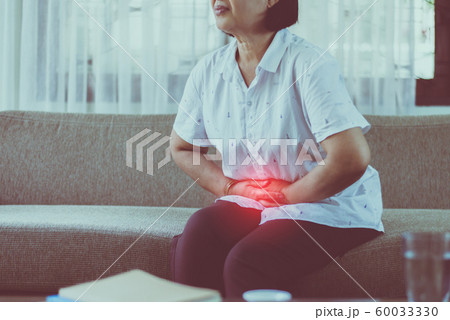 Elderly asian woman having stomachache while sitting on sofa at home,Senior female suffering from abdominal pain Elderly asian woman having stomachache while sitting on sofa at home,Senior female suffering from abdominal pain 60033330