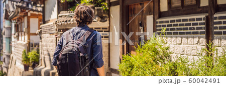Young man tourist in Bukchon Hanok Village is one of the famous place for Korean traditional houses Young man tourist in Bukchon Hanok Village is one of the famous place for Korean traditional houses 60042491