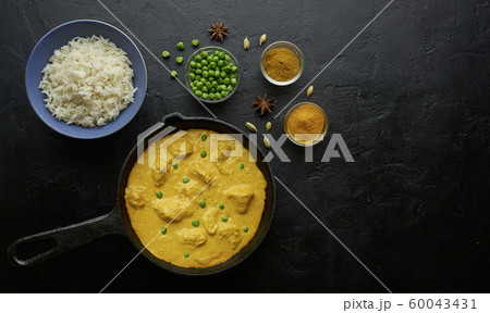 Cooking tasty butter chicken curry dish with rice in a cast iron pan Cooking tasty butter chicken curry dish with rice in a cast iron pan 60043431