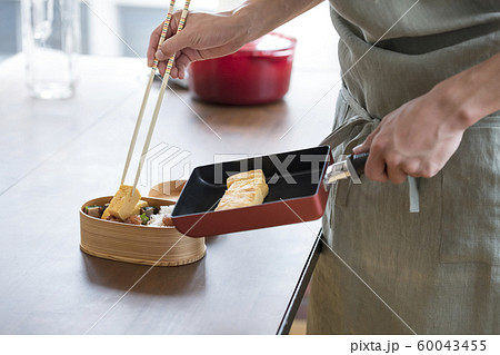 お弁当箱に卵焼きを詰める男性の手元　料理男子　イメージ 60043455