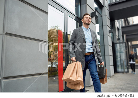 Adult man with shopping bags walking outdoor Adult man with shopping bags walking outdoor 60043783