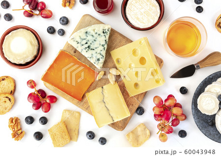 Cheese platter, a flat lay top shot on a white background. Blue cheese, red Leicester, Emmental, goat cheese, Brie and others with wine, fruits, nuts 60043948