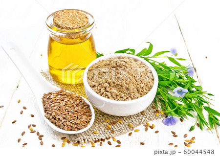 Flour linen in bowl with seeds and oil on board 60044548