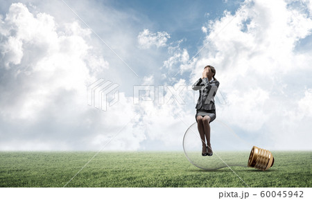 Young woman sitting on big light bulb Young woman sitting on big light bulb 60045942