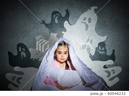 Scared girl with pillow hiding under blanket Scared girl with pillow hiding under blanket 60046232