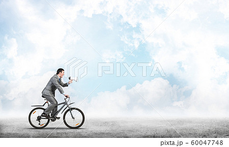 Businessman with megaphone on bike Businessman with megaphone on bike 60047748