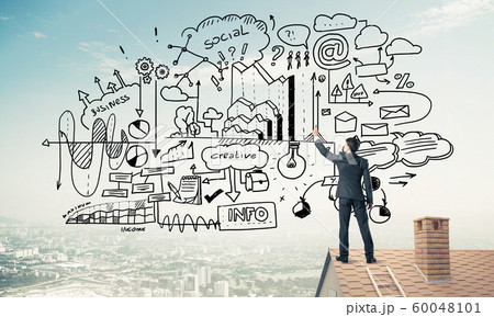 Rear view of businessman on house roof drawing his new business Rear view of businessman on house roof drawing his new business 60048101