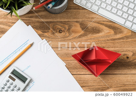 Wooden office desk with red origami boat Wooden office desk with red origami boat 60049922