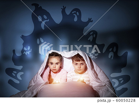 Scared children in pajamas with flashlights Scared children in pajamas with flashlights 60050228