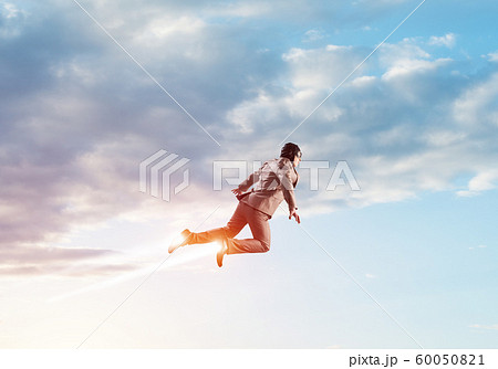 Businessman in suit and aviator hat flying in sky 60050821