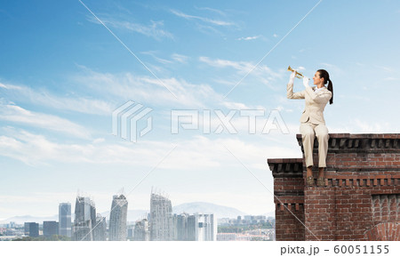 Young woman playing trumpet and sitting on roof Young woman playing trumpet and sitting on roof 60051155