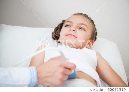 Sonographer moving transducer on belly of girl 60051519