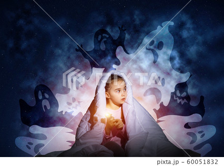 Scared girl with flashlight under blanket Scared girl with flashlight under blanket 60051832