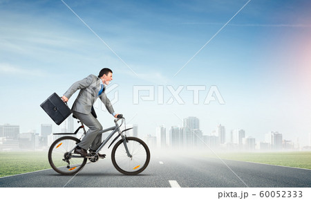 Man wearing business suit riding bicycle outdoor. 60052333