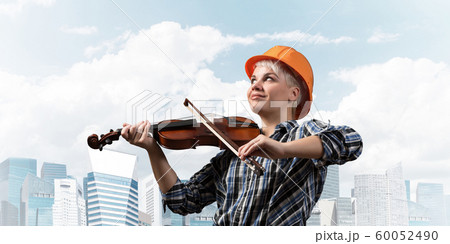 Beautiful woman in safety helmet playing violin 60052490