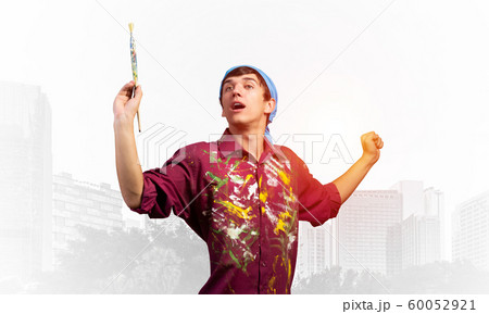 Young emotional artist gesturing with paintbrush Young emotional artist gesturing with paintbrush 60052921