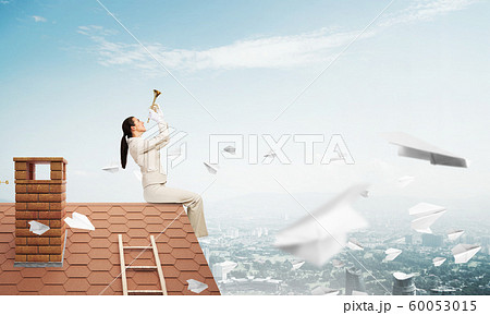 Beautiful young woman playing trumpet on roof 60053015