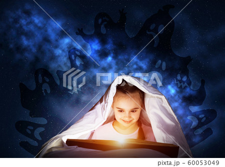 Enthusiastic little girl reading book in bed 60053049