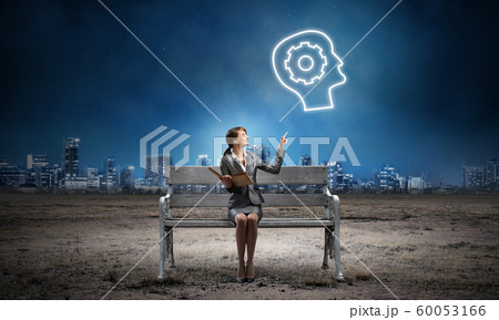 Young woman holding open book on bench 60053166