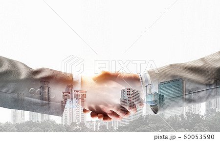 Business handshake as idea for unity and cooperation or greeting. Mixed media Business handshake as idea for unity and cooperation or greeting. Mixed media 60053590