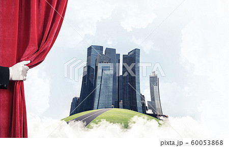 Modern cityscape behind drapery curtain and hand opening it 60053868