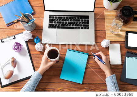 Business woman writing in notebook at office desk Business woman writing in notebook at office desk 60053969