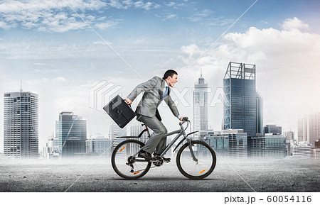 Man wearing business suit riding bicycle outdoor. 60054116